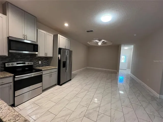 a kitchen with stainless steel appliances granite countertop a refrigerator and a stove top oven