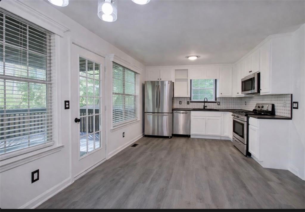 22 Nottingham Drive Northwest Cartersville, GA 30121 - Photo 13 of 36 a kitchen with a refrigerator a stove top oven and white cabinets with wooden floor