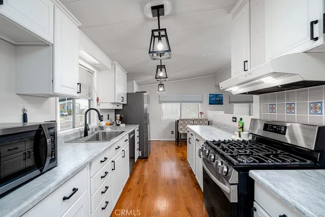 a kitchen with stainless steel appliances granite countertop a stove a sink dishwasher a refrigerator and wooden cabinets