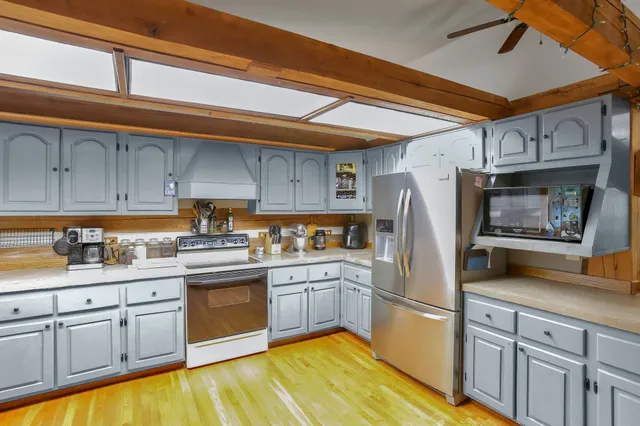 a kitchen with stainless steel appliances granite countertop a refrigerator a sink dishwasher a stove and white countertops with cabinets