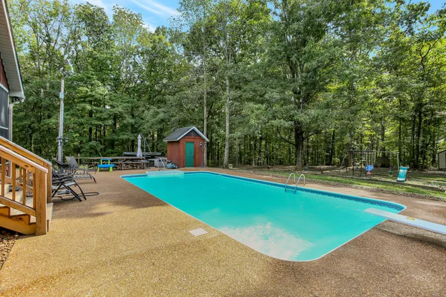 a view of a swimming pool with a patio and a yard