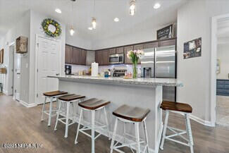 5573 Casavedra Court Jacksonville, FL 32244 - Photo 7 of 34 a kitchen with stainless steel appliances kitchen island granite countertop a dining table chairs and white cabinets