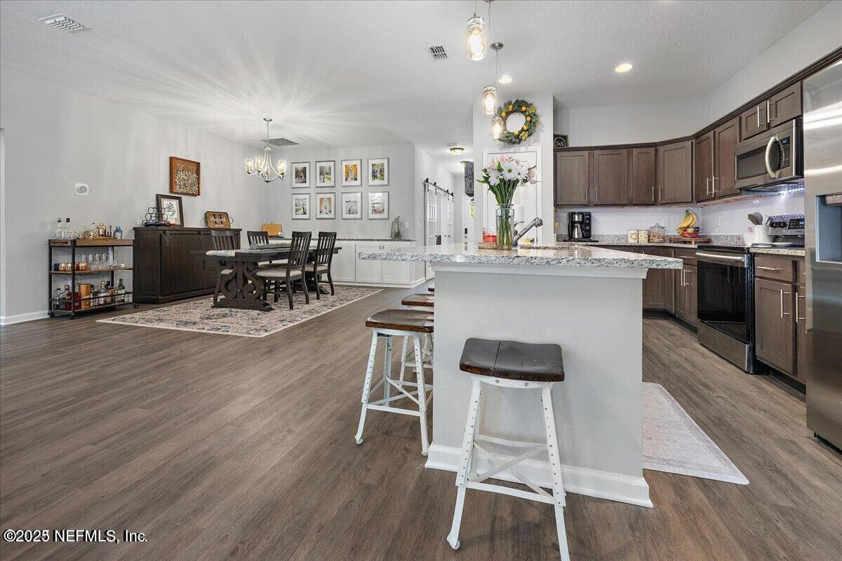 5573 Casavedra Court Jacksonville, FL 32244 - Photo 9 of 34 a kitchen with stainless steel appliances granite countertop a stove top oven a sink dishwasher a dining table and chairs with wooden floor