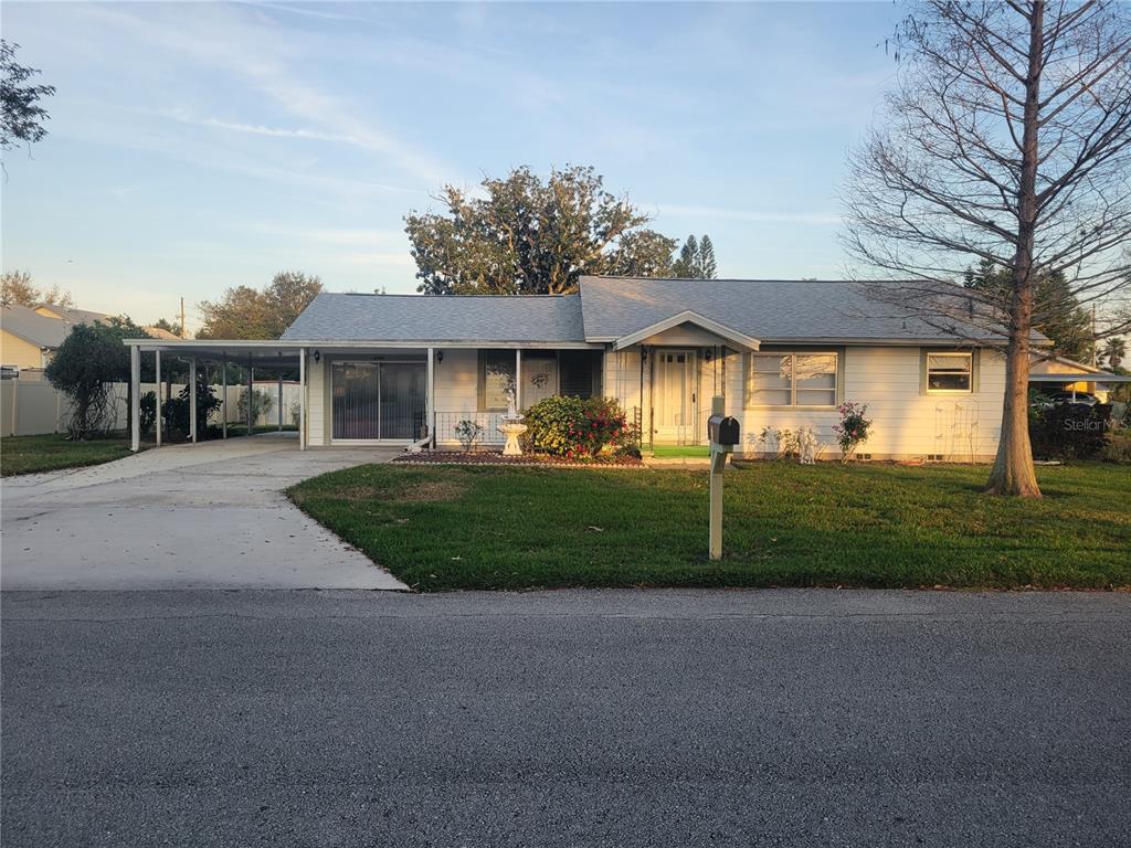a view of house in front of a big yard with potted plants