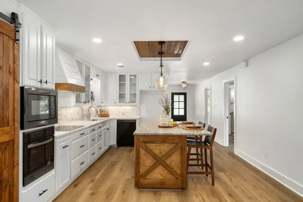 a kitchen with granite countertop a table chairs stainless steel appliances and cabinets