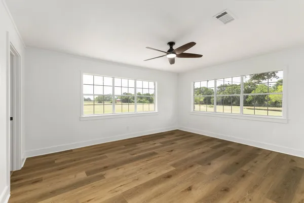 a view of a big room with wooden floor and a ceiling fan