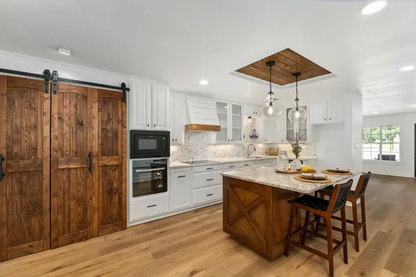 a kitchen with stainless steel appliances kitchen island granite countertop a table chairs and a refrigerator