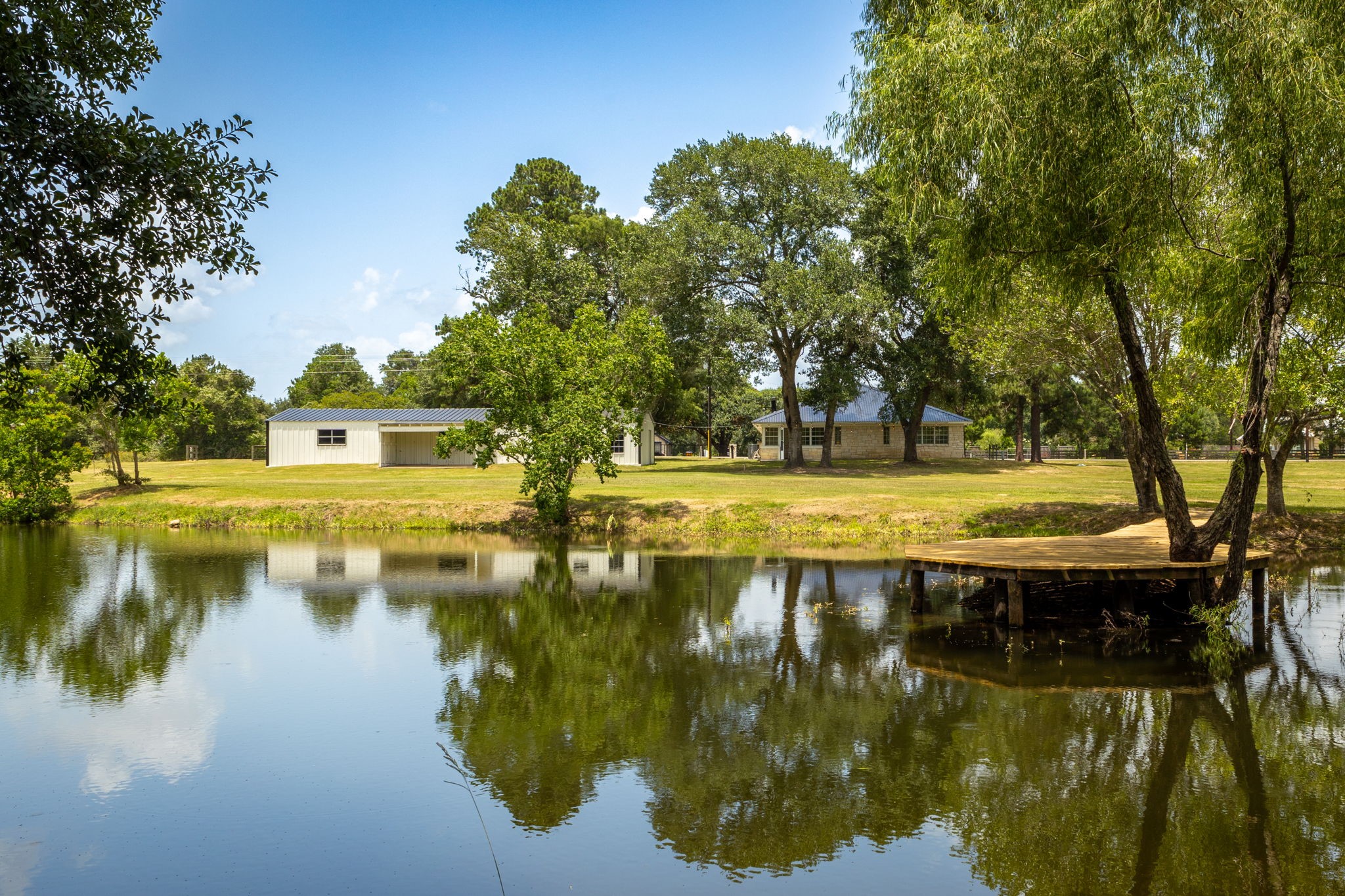 1195 Track Road New Ulm, TX 78950 - Photo 7 of 49 Tranquil pond with a charming pier, surrounded by lush greenery—perfect for relaxation and outdoor enjoyment.