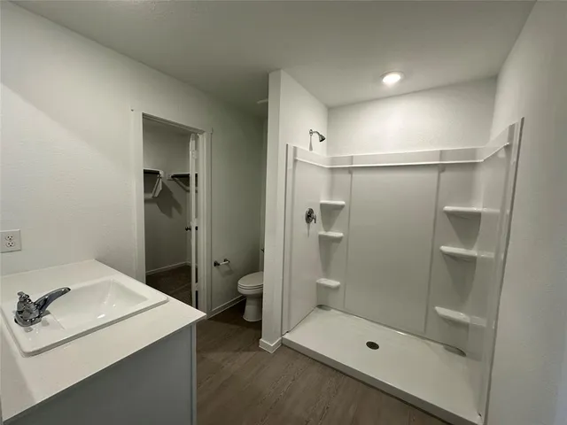 a bathroom with a shower sink mirror and toilet