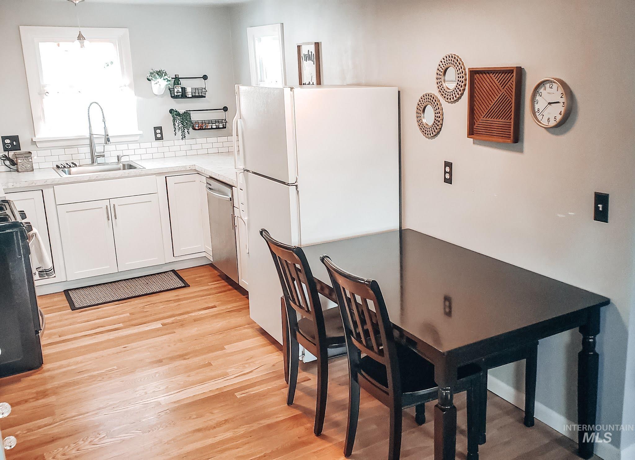 814 Baker Street Boise, ID 83706 - Photo 7 of 26 Kitchen featuring wood-finish flooring, white cabinetry, subway tile backsplash, and a stainless steel sink with a gooseneck faucet