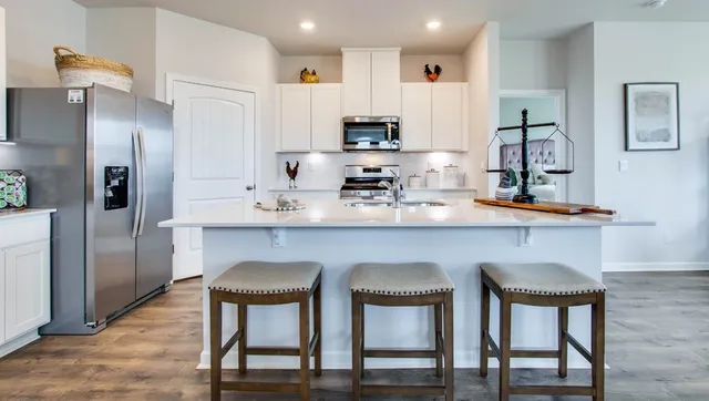 a kitchen with stainless steel appliances granite countertop a chairs a sink and a refrigerator