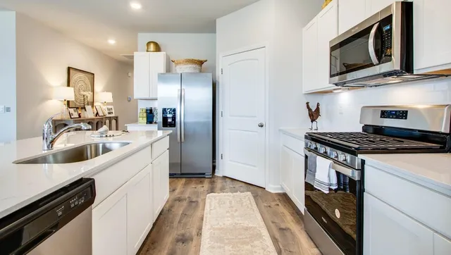 a kitchen with stainless steel appliances granite countertop a stove microwave and sink
