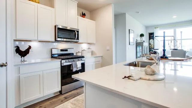 a kitchen with a sink a stove and white cabinets