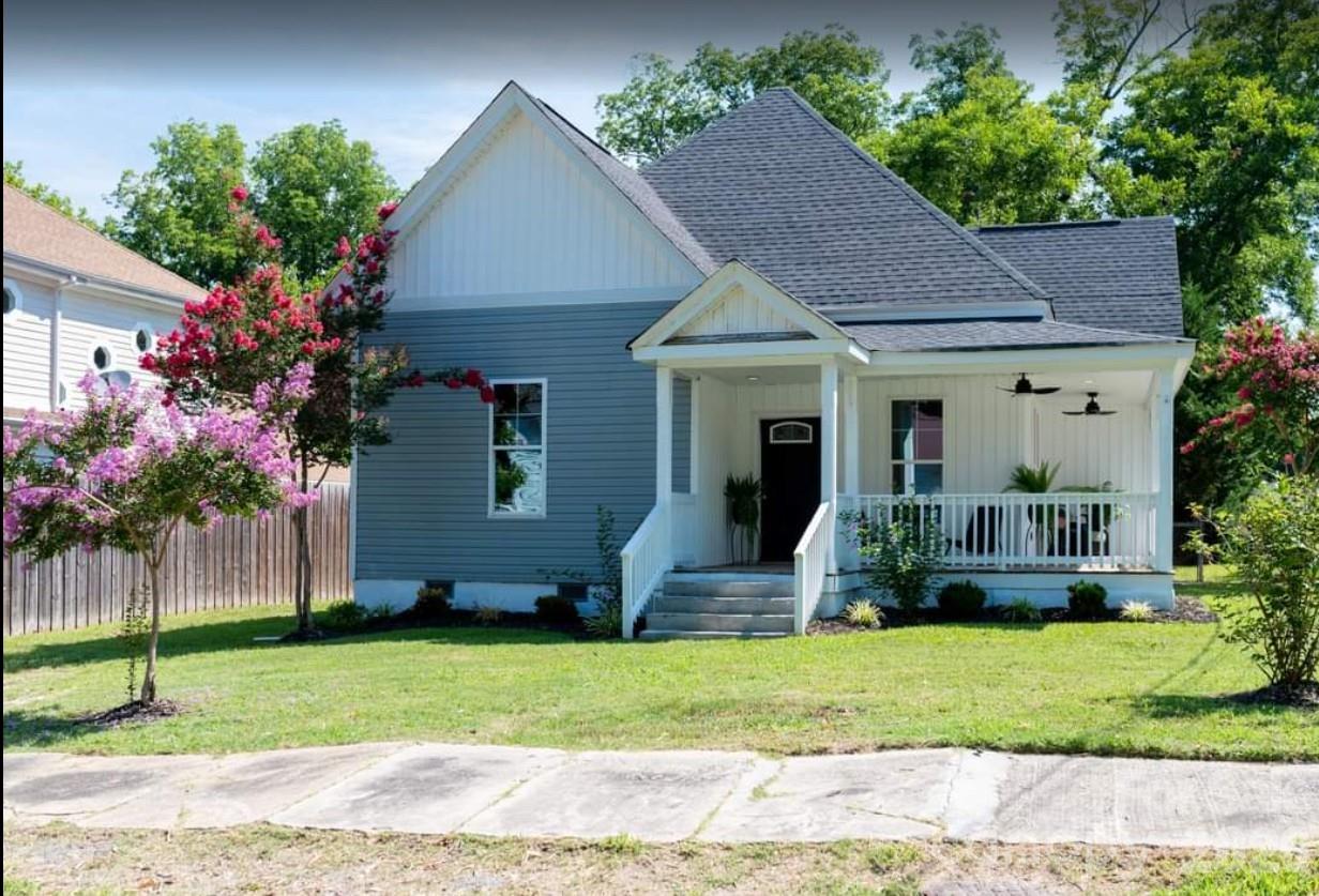 a front view of a house with a yard and potted plants
