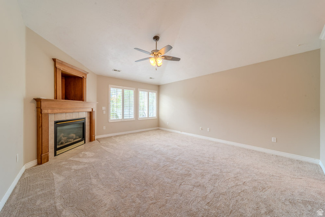 598 Hollow Creek Road Draper, UT 84020 - Photo 88 of 110 Spacious room featuring a fireplace with a wood-finish mantel and tile surround, built-in shelving, carpet flooring, a ceiling fan, and multiple windows with plantation shutters