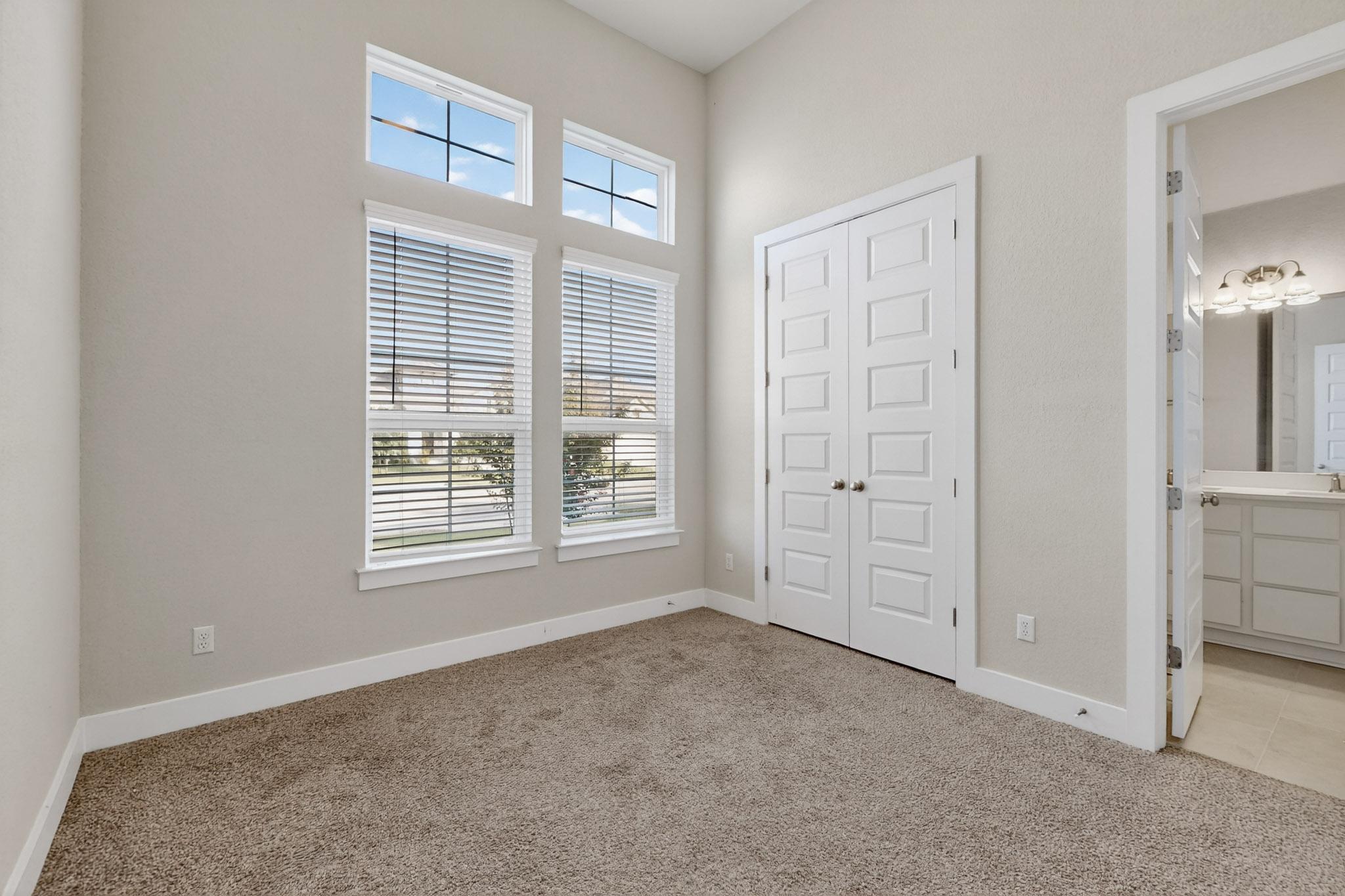 20912 Carries Ranch Road Pflugerville, TX 78660 - Photo 6 of 20 High ceilings and tall windows optimize natural light across this versatile bedroom space.