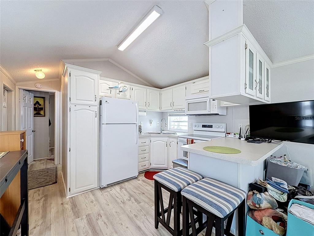 2092 Culbreath Road, Unit A42 Brooksville, FL 34602 - Photo 67 of 70 a kitchen with a refrigerator a stove and a dining table with wooden floor