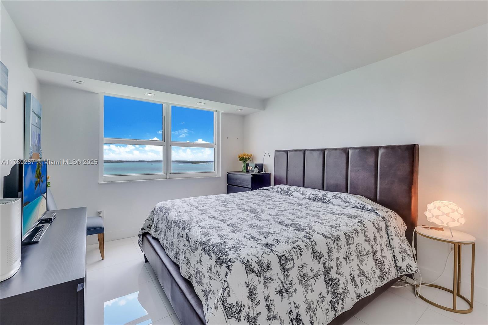 1155 Brickell Bay Drive, Unit 1210 Miami, FL 33131 - Photo 7 of 18 a bedroom with a bed and a dresser with wooden floor