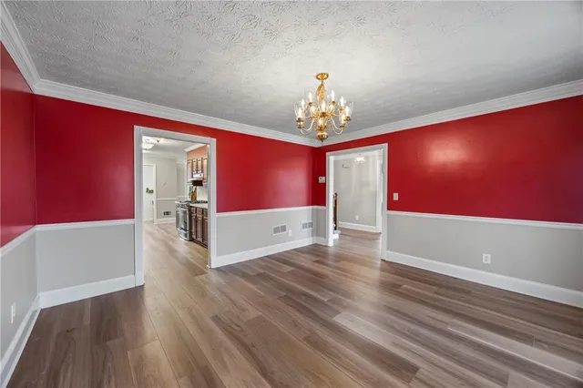 an empty room with chandelier fan and windows