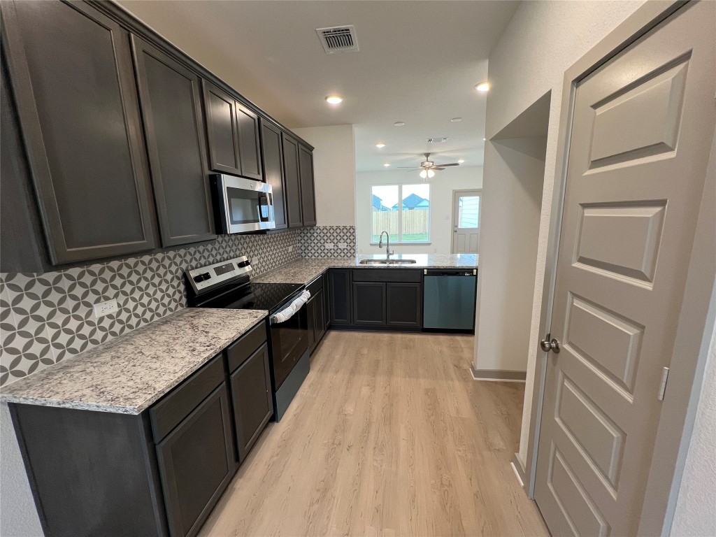 270 Boatright Boulevard Jarrell, TX 76537 - Photo 2 of 7 Kitchen featuring appliances with stainless steel finishes, light stone counters, tasteful backsplash, light wood-style floors, and recessed lighting