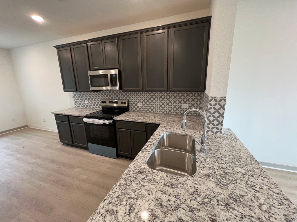 270 Boatright Boulevard Jarrell, TX 76537 - Photo 3 of 7 Kitchen with stainless steel appliances, tasteful backsplash, light stone counters, and recessed lighting