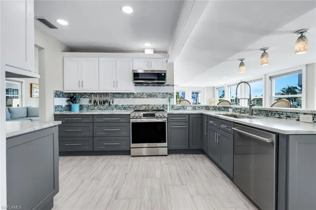 a kitchen with stainless steel appliances granite countertop a stove top oven a sink dishwasher and white cabinets with wooden floor