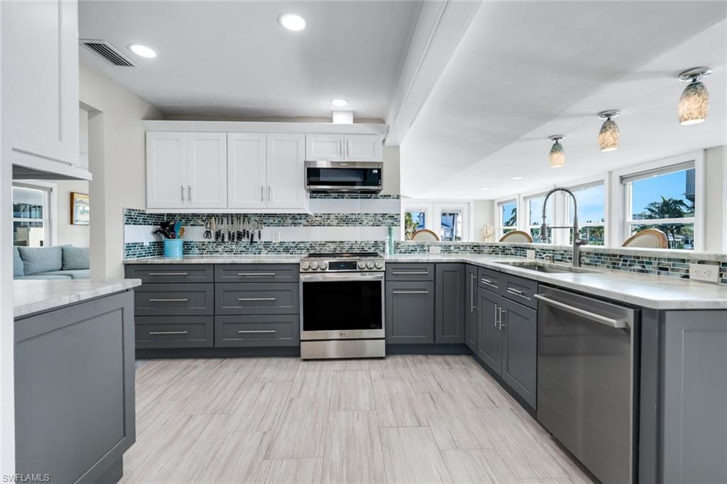 100 Tarpon Road Fort Myers Beach, FL 33931 - Photo 9 of 49 a kitchen with stainless steel appliances granite countertop a stove top oven a sink dishwasher and white cabinets with wooden floor
