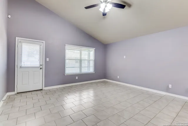 en empty room with windows and chandelier fan