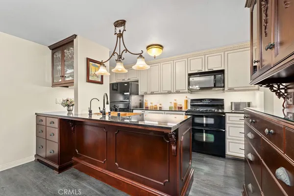 a kitchen with stainless steel appliances a sink a stove top oven a chimney cabinets and a window