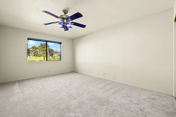 an empty room with window and ceiling fan