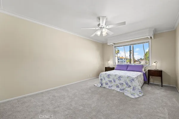 a spacious bedroom with a large bed and a chandelier fan