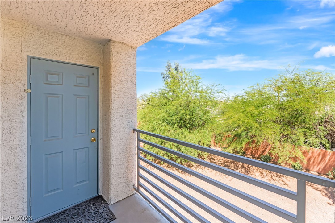 3318 North Decatur Boulevard, Unit 2152 Las Vegas, NV 89130 - Photo 22 of 58 A quiet private patio retreat, featuring a blue entry door and views of vibrant green foliage.
