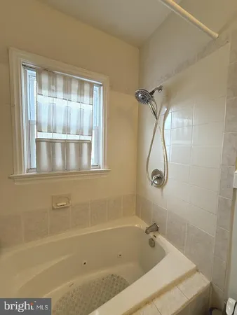 a bathroom with a tub a shower and a window