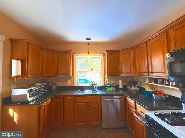 a kitchen with stainless steel appliances granite countertop a sink a stove a refrigerator cabinets and a window