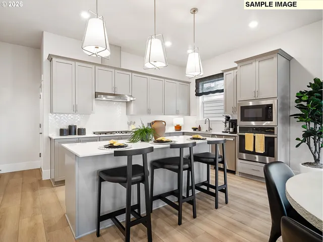 a kitchen with stainless steel appliances a table chairs refrigerator and cabinets