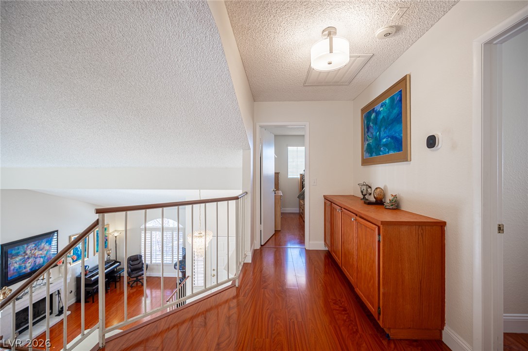 718 Rusty Spur Drive Henderson, NV 89014 - Photo 35 of 50 Rich hardwood floors lead the way down a naturally illuminated upstairs hallway.