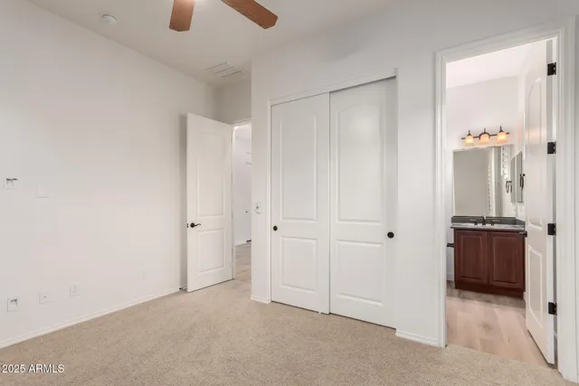 an empty room with closet and a chandelier fan