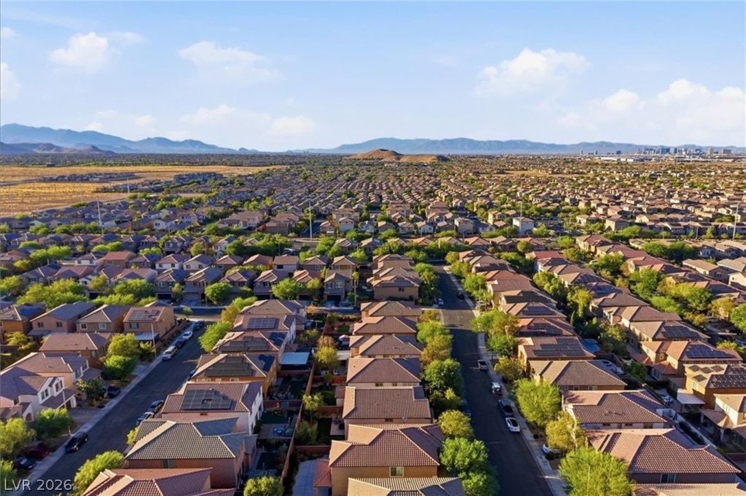 11009 Prairie Grove Road Las Vegas, NV 89179 - Photo 45 of 49 An aerial perspective reveals a vast community of homes under a bright sky, framed by distant mountains.