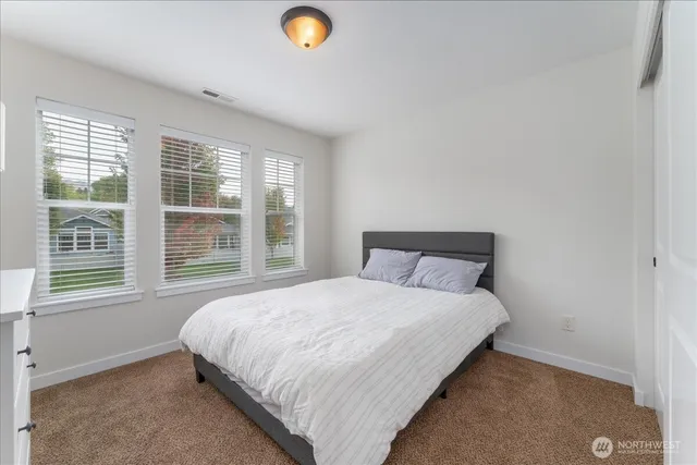 a bedroom with a bed and a lamp on dresser