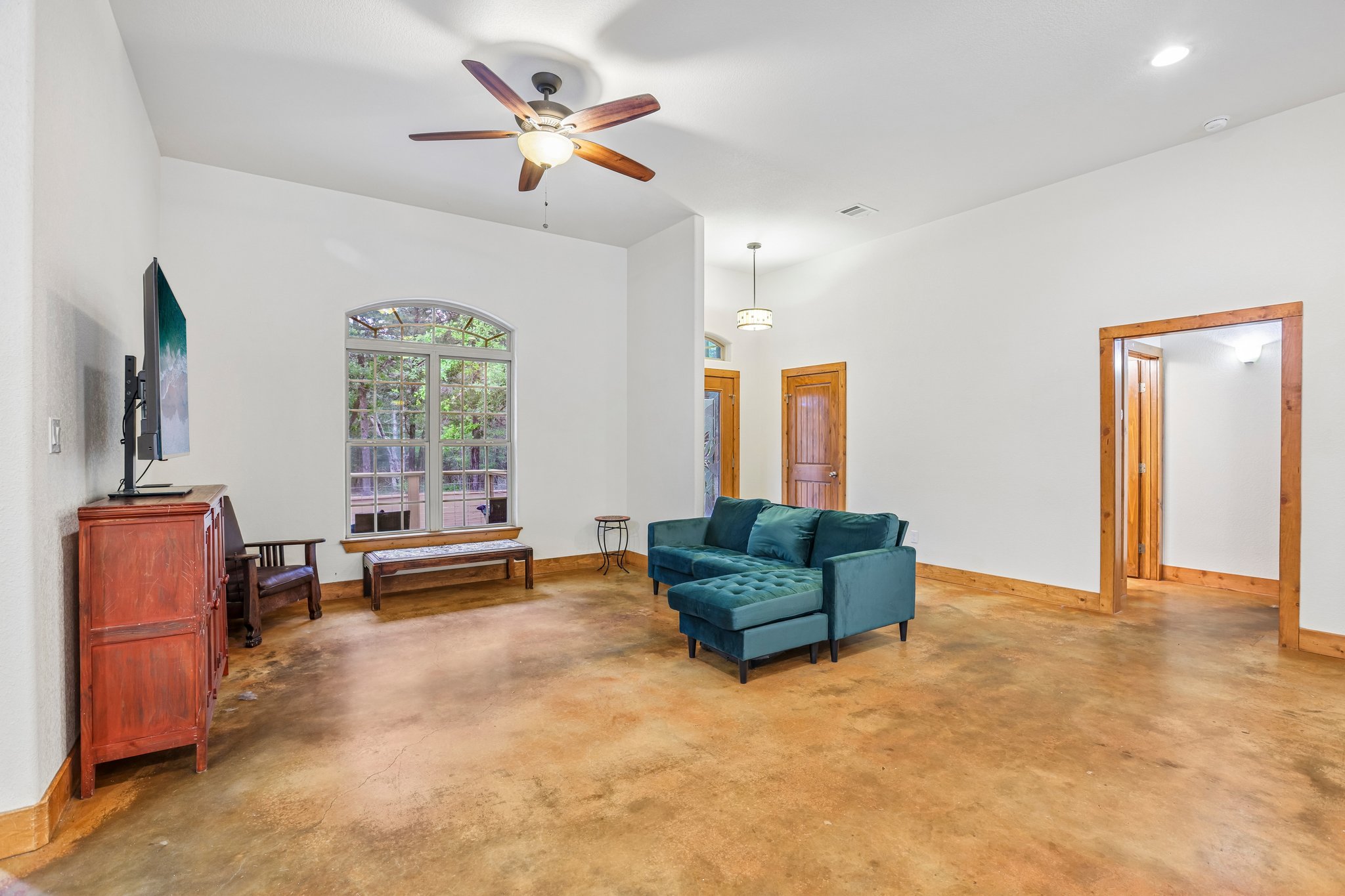 267 Corral Road Smithville, TX 78957 - Photo 11 of 40 Spacious living area featuring high vaulted ceilings, an arched window, wood-finish baseboards and door frames, a ceiling fan with integrated lighting, and polished concrete flooring