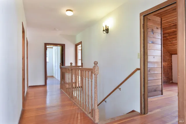 a view of a hallway with wooden floor and windows