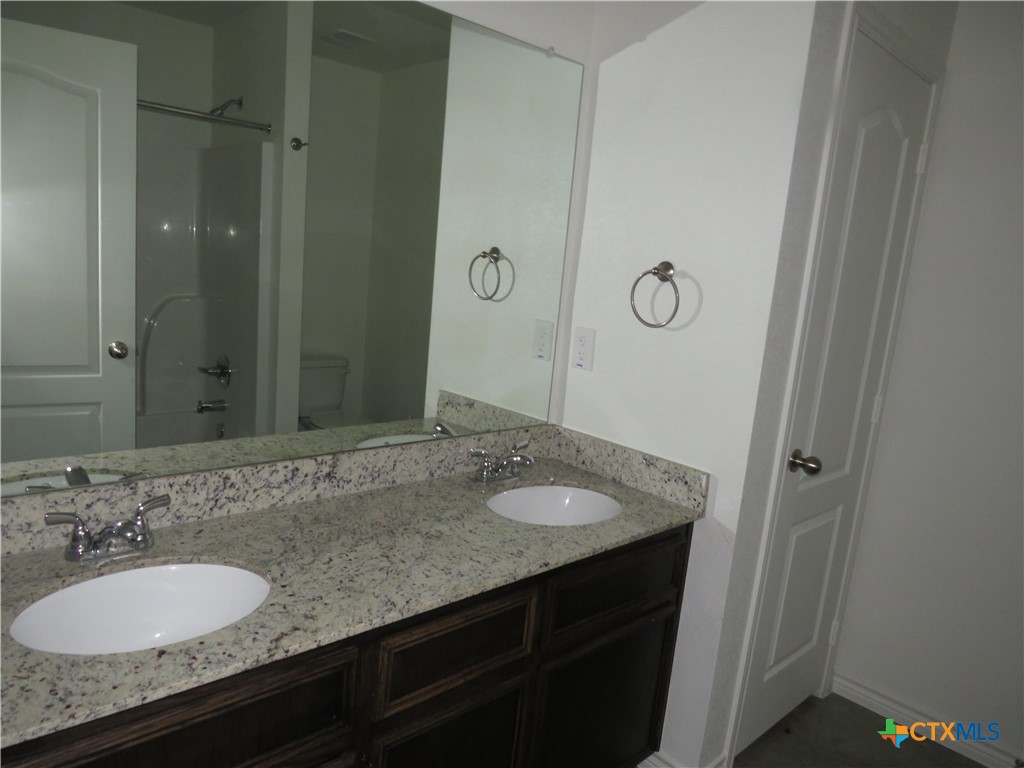 1004 Barbara Jordan Street, Unit B Killeen, TX 76543 - Photo 12 of 13 a bathroom with a granite countertop sink and a mirror