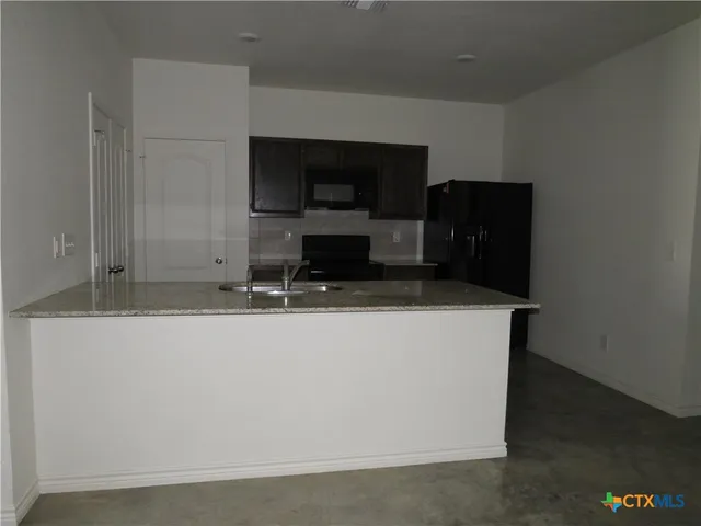 a living room with stainless steel appliances kitchen island sink and refrigerator