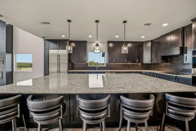 a kitchen with granite countertop a table chairs stove and refrigerator