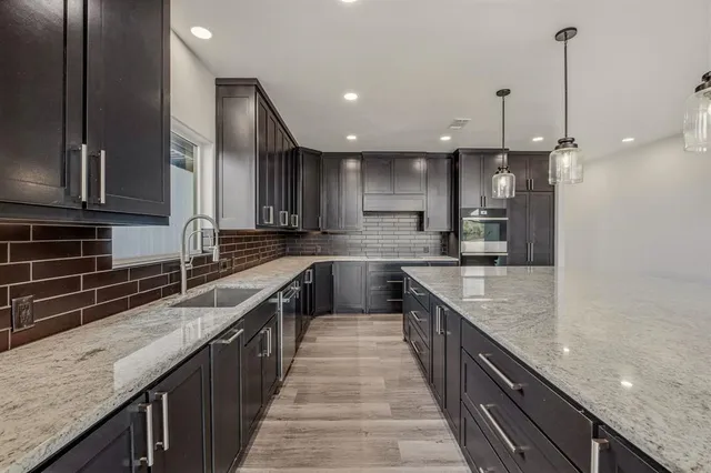 a kitchen with kitchen island granite countertop a sink a counter top stainless steel appliances and cabinets