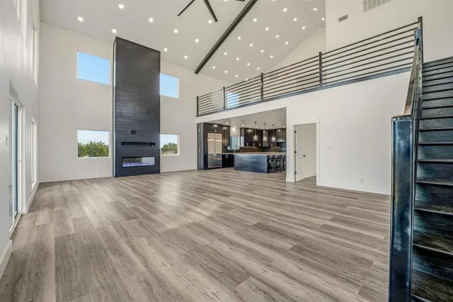 an empty room with wooden floor kitchen view and a window