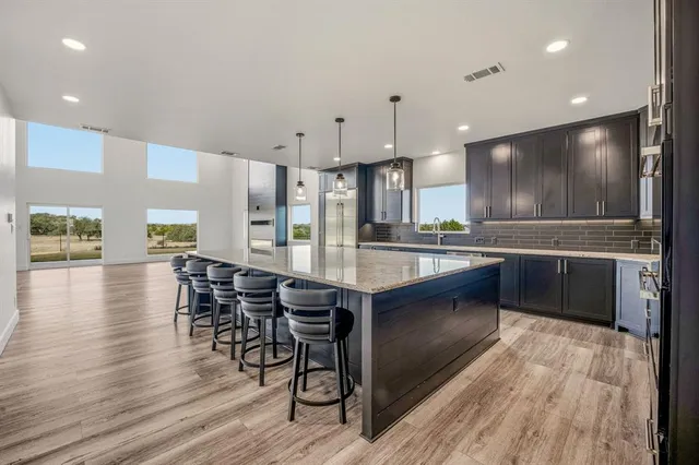 a kitchen with stainless steel appliances kitchen island granite countertop a table chairs sink and cabinets