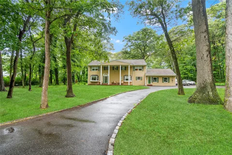 a view of a house next to a big yard and large trees