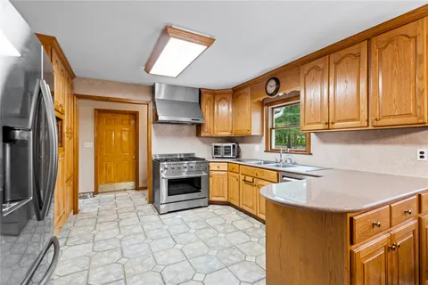 a kitchen with granite countertop a sink cabinets stainless steel appliances and a window