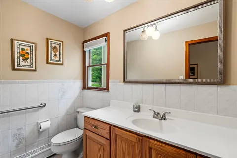 a bathroom with a toilet a sink a mirror and a window